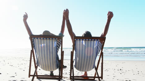Senior-couple-relaxing-on-sunlounger-at-beach
