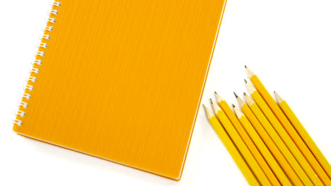 Lápices-De-Color-Amarillo-Con-Libro-Sobre-Fondo-Blanco.