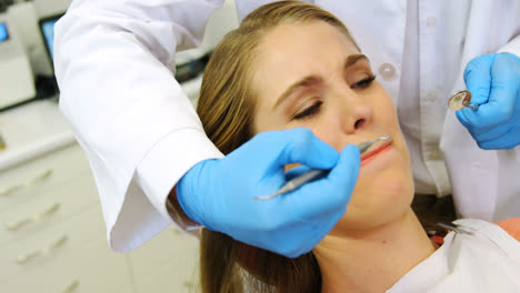 Dentists-examining-a-female-patient-with-tools