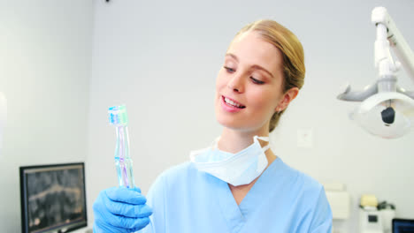 Portrait-of-female-nurse-holding-toothbrushes