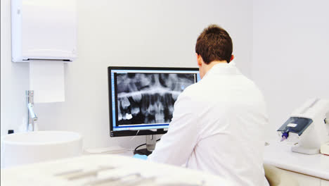 Attentive-dentist-examining-x-ray-report-on-computer