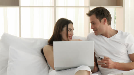 Couple-using-a-laptop-in-the-bedroom
