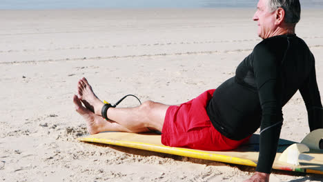 Senior-man-with-surfboard-relaxing-on-beach