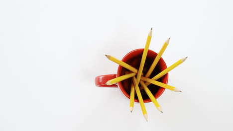 Yellow-color-pencils-kept-in-red-mug-on-white-background