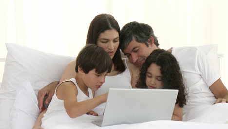 Eltern-Und-Kinder-Mit-Einem-Laptop-Im-Bett