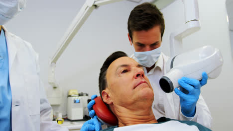 Dentist-examining-a-male-patient-with-dental-tool