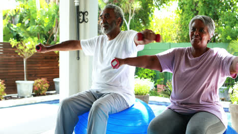 Senior-couple-exercising-with-dumbbell-at-home