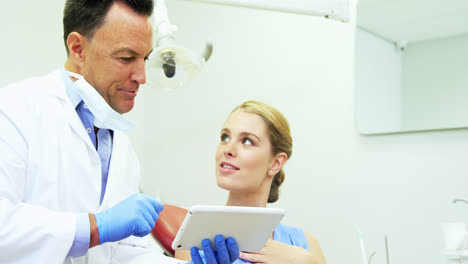 Dentist-discussing-over-digital-tablet-with-female-patient