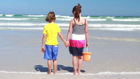 Siblings-holding-hands-and-standing-on-the-beach
