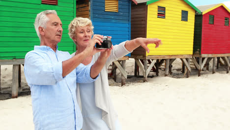 Senior-couple-clicking-photo-on-camera-at-the-beach