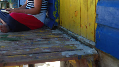 Girl-using-digital-tablet-near-colorful-beach-hut