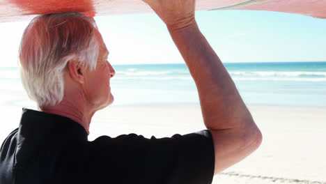 älterer-Mann-Im-Neoprenanzug-Trägt-Surfbrett-über-Dem-Kopf