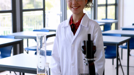 Portrait-of-schoolgirl-standing-with-various-experiment-equipments