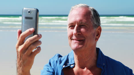 Älterer-Mann,-Der-Am-Strand-Einen-Videoanruf-Mit-Dem-Mobiltelefon-Führt