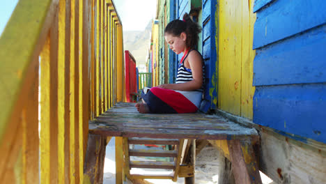 Girl-reading-book-near-colorful-beach-hut-