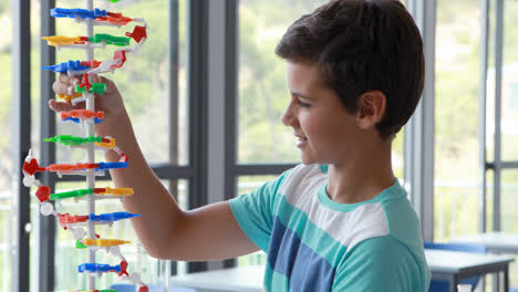 Attentive-schoolboy-experimenting-molecule-model-in-laboratory