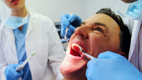 Dentists-examining-a-male-patient-with-tools