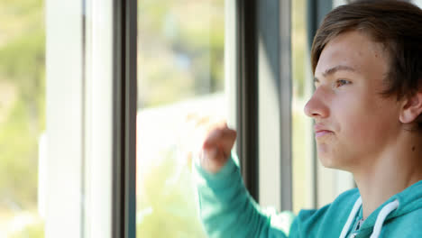 Thoughtful-schoolboy-looking-through-window
