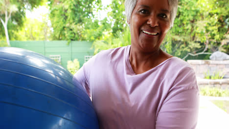 Senior-woman-holding-fitness-ball-at-home
