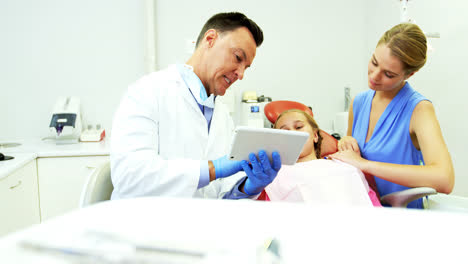 Dentist-interacting-with-young-patient-over-digital-tablet