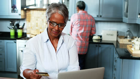 Senior-woman-doing-online-shopping-on-laptop-in-kitchen-at-home