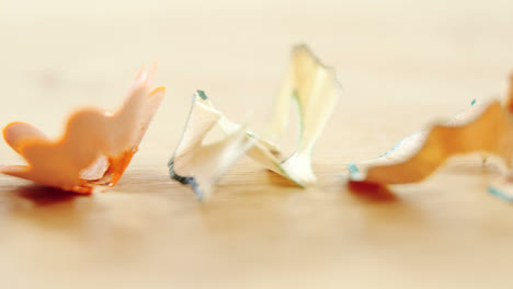 Various-colored-pencil-shavings-arranged-on-wooden-background