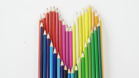 Colored-pencils-arranged-in-heart-shape-on-white-background