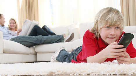 Boy-watching-television-on-floor-with-his-parents-on-sofa