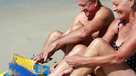 Senior-couple-wearing-flippers-on-beach