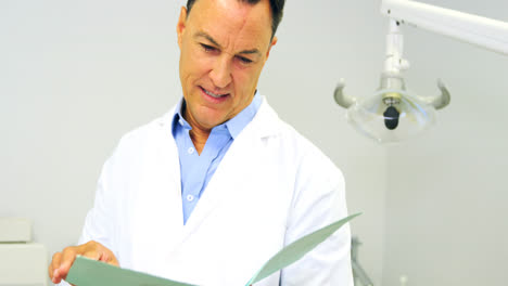 Portrait-of-smiling-dentist-looking-at-file