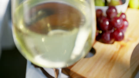 Close-up-of-white-wine-glass-and-fruits-on-table
