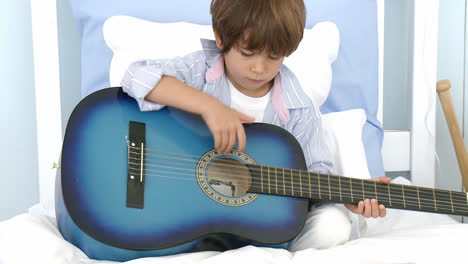 Kleiner-Junge-Spielt-Gitarre-Auf-Dem-Bett