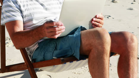 Senior-man-video-chatting-on-laptop-at-beach