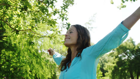 Woman-standing-with-arms-outstretched-in-the-park