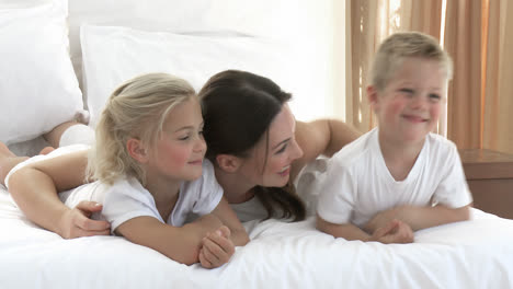 Attractive-mother-and-children-playing-in-bed