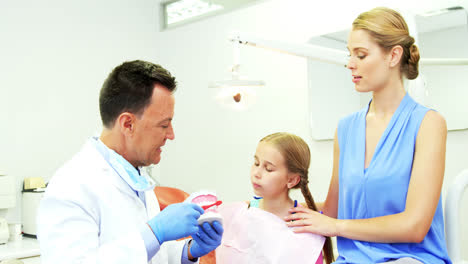 Dentist-showing-young-patient-how-to-brush-teeth