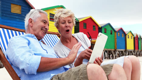Senior-couple-using-digital-tablet-at-the-beach