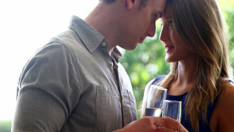 Couple-looking-face-to-face-and-holding-champagne-flutes-in-restaurant