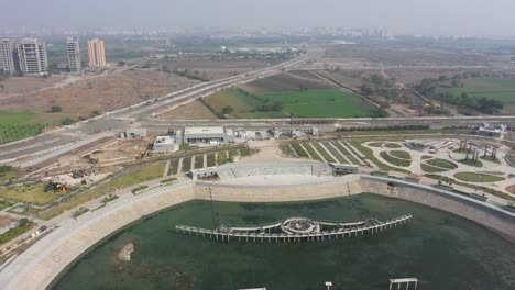 Cámara-De-Drones-Con-Vista-De-Drone-Del-Lago-Rajkot-Atal-Avanzando-Mostrando-Grandes-Caminatas-Y-Grandes-Guardias-Y-Un-Gran-Reloj,-Nuevo-Hipódromo-De-Rajkot,-Atal-Sarovar