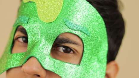 Young-man-using-glittered-cartoon-green-mask-and-smiling-at-camera