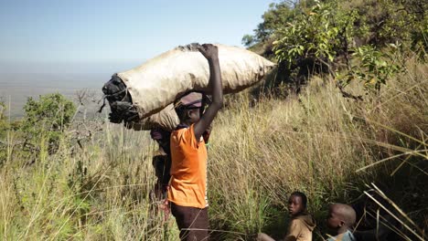 Local-children-in-a-remote-village-of-East-Africa-carrying-sacks-of-food-and-charcoal-on-their-heads