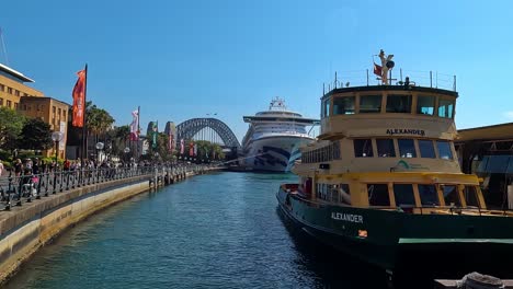 Ferry-and-cruise-ship-docked-at-Sydney-Harbour-with-the-Harbour-Bridge-in-the-background,-clear-day