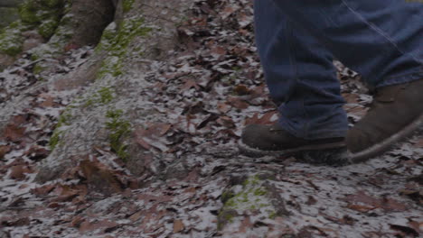 Zeitlupe-Der-Füße-Eines-Mannes-In-Wanderschuhen-Und-Blue-Jeans-Springt-Von-Einem-Moosbedeckten-Felsbrocken-In-Der-Wildnis-Auf-Den-Mit-Blättern-Bedeckten-Waldboden
