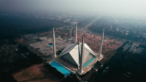 Faisal-Mosque-in-Islamabad-with-surrounding-landscape-in-daylight,-aerial-shot