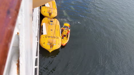 passengers-don-life-jackets-and-safety-gear-as-they-ascend-into-the-cruise-ship's-lifeboat,-ensuring-readiness-for-any-maritime-emergency,-highlighting-the-ship's-commitment-to-passenger-safety