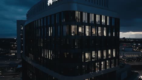 Vista-Aérea-Por-Drones-Del-Logotipo-De-Huawei-En-La-Parte-Superior-Del-Edificio-De-Oficinas-Por-La-Noche