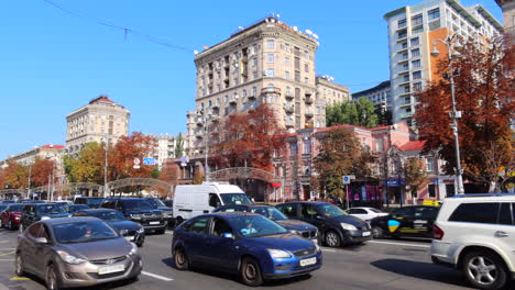 Khreshchatyk-main-street-of-Kyiv-city-capital-in-Ukraine,-sunny-weather-and-cars-driving,-tall-apartment-buildings,-4K-shot