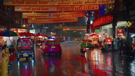 Taxi-Bangok-Conduciendo-Por-Una-Calle-Lluviosa-Con-Luces-De-Neón-Y-Reflejos-Brillantes-En-Chinatown