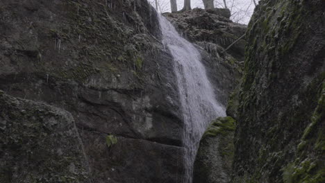 slow-motion-stationary-shot-of-a-waterfall-running-down-a-rocky-cliff-in-northeastern-Ohio-shot-from-below