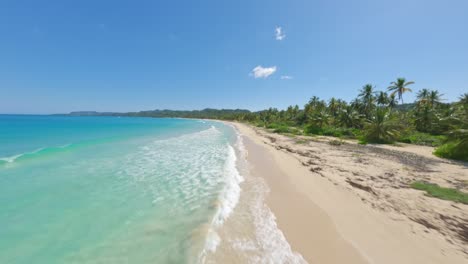 Drone-fpv-flight-along-sandy-beach-with-transparent-water